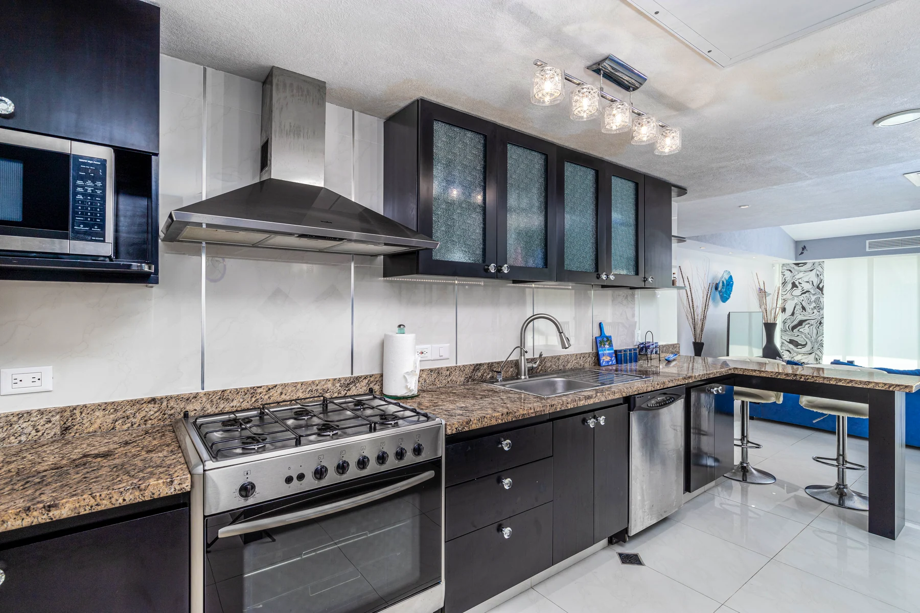 Gas kitchen with steel range, hood and granite bar