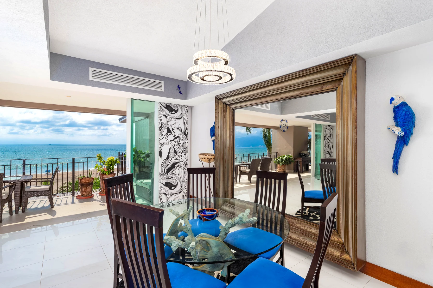 Glass dining table with wooden chairs and the mirror that gives the sea back