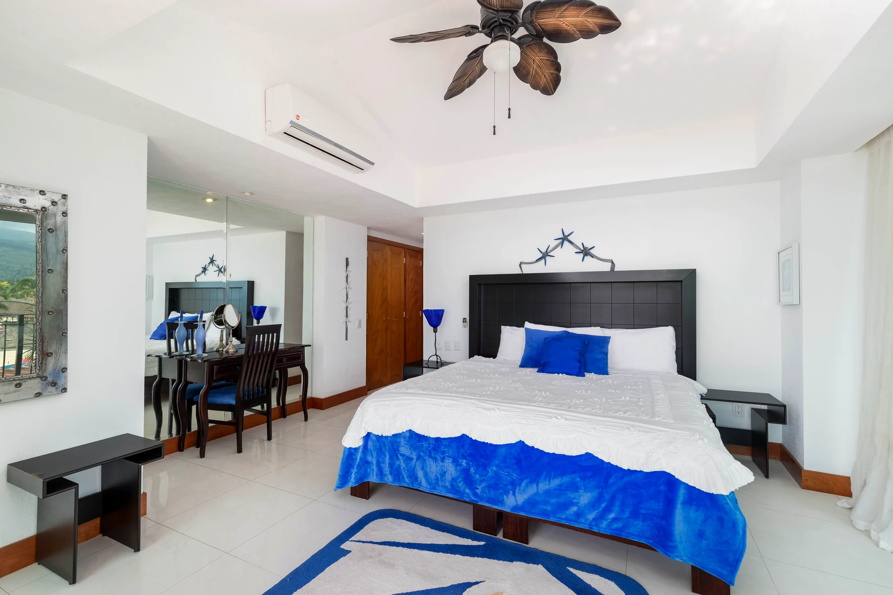 Bedroom with wooden headboard, blue linens and a mirror