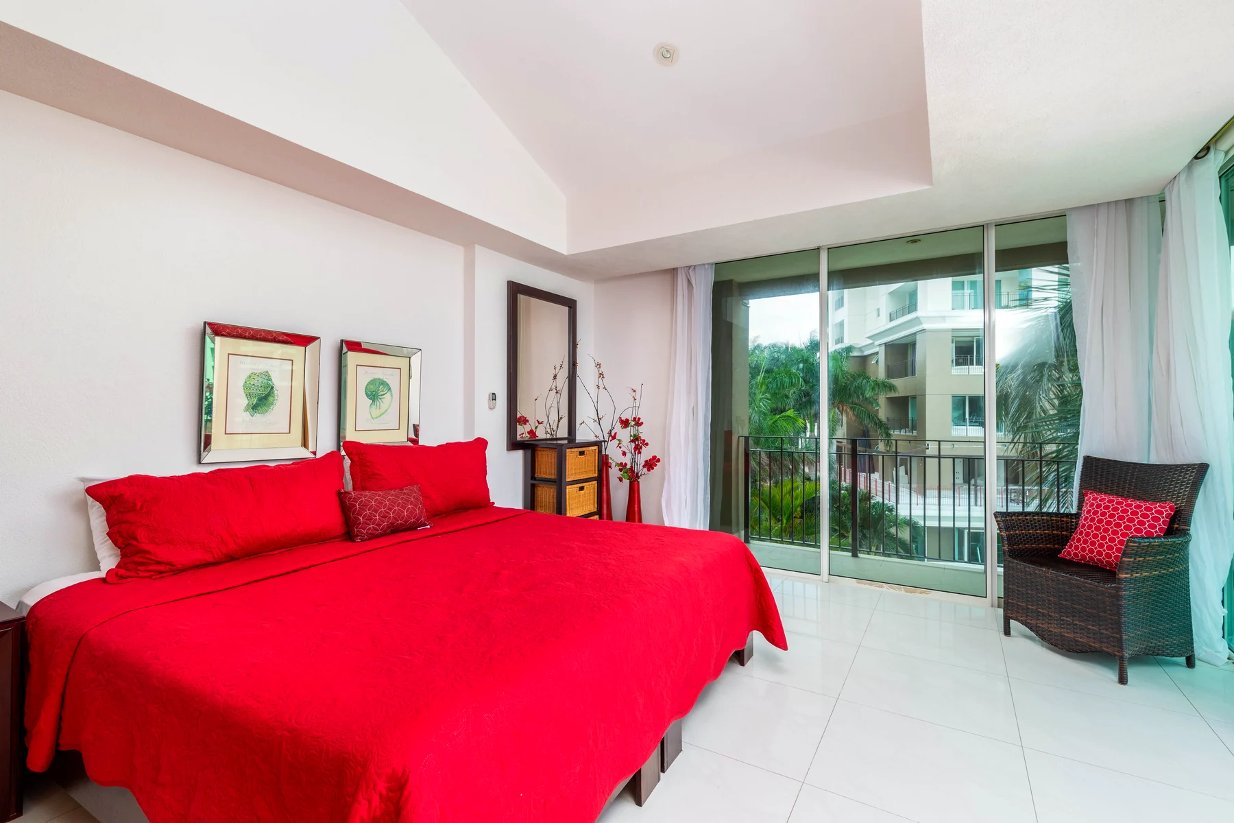 Bedroom with red linens and access to the balcony