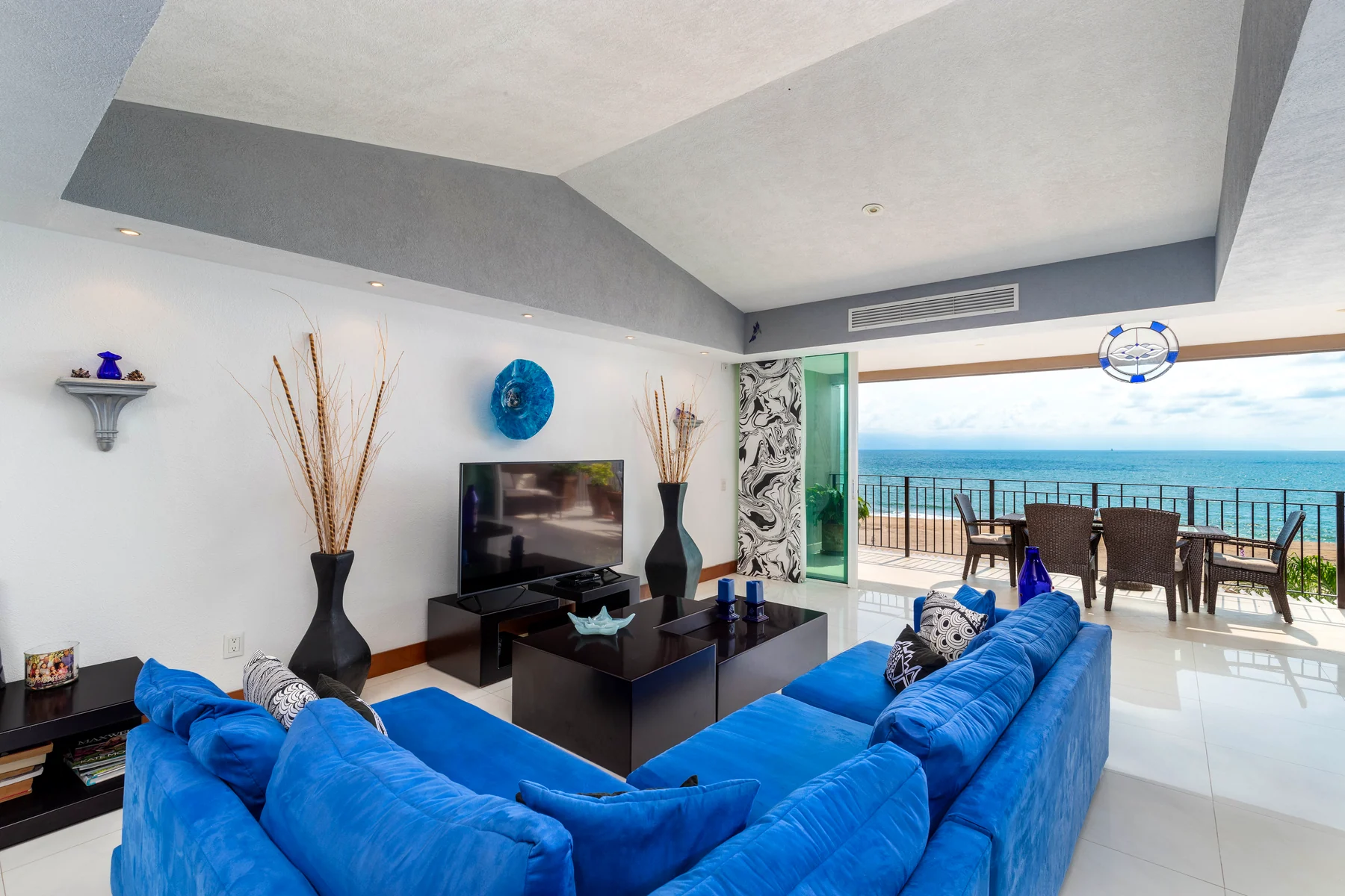 Sitting room with blue sofa, television and access to the terrace
