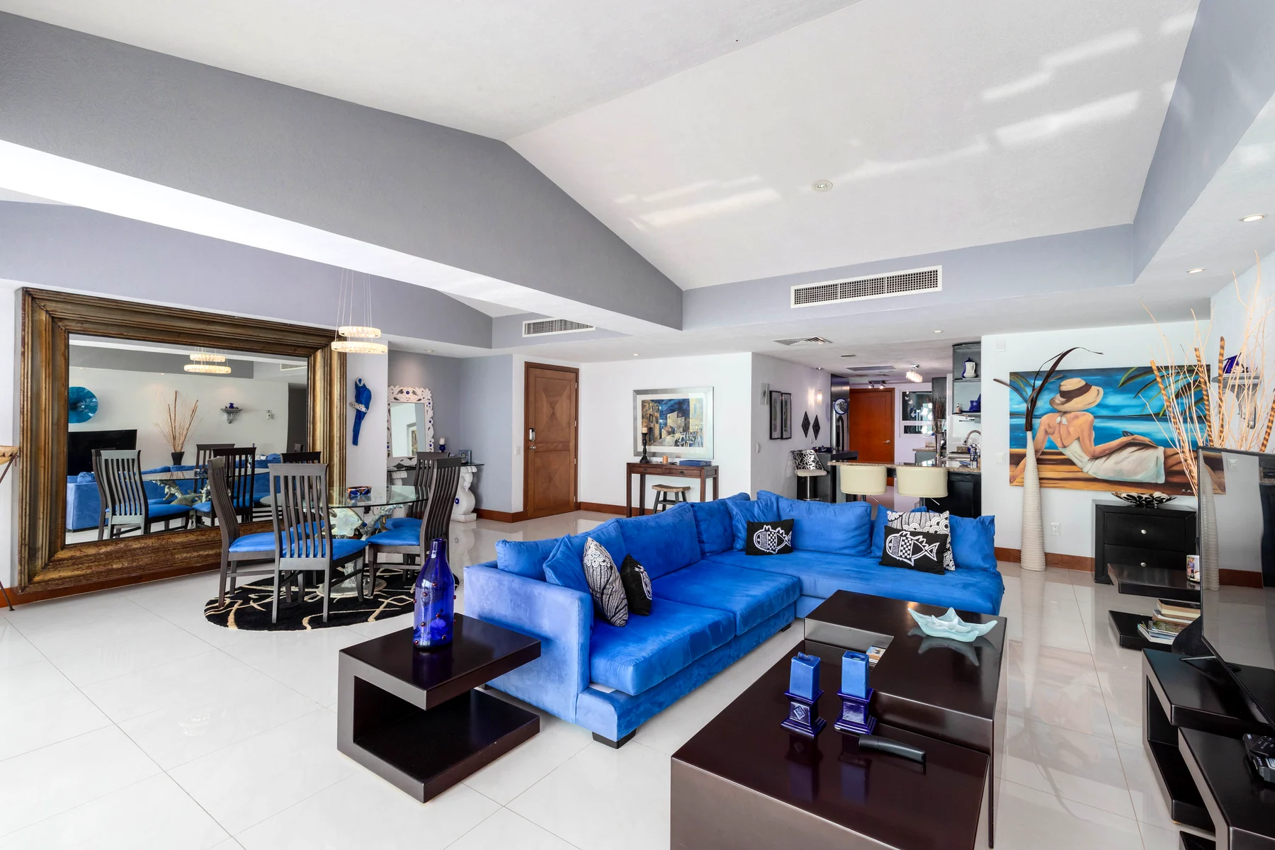 The living room with the large wall mirror and the blue seating